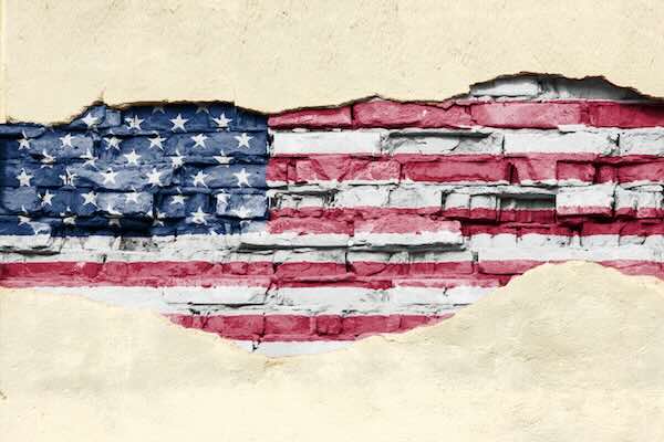 National flag of USA on a brick background. Brick wall with partially destroyed plaster, background or texture.