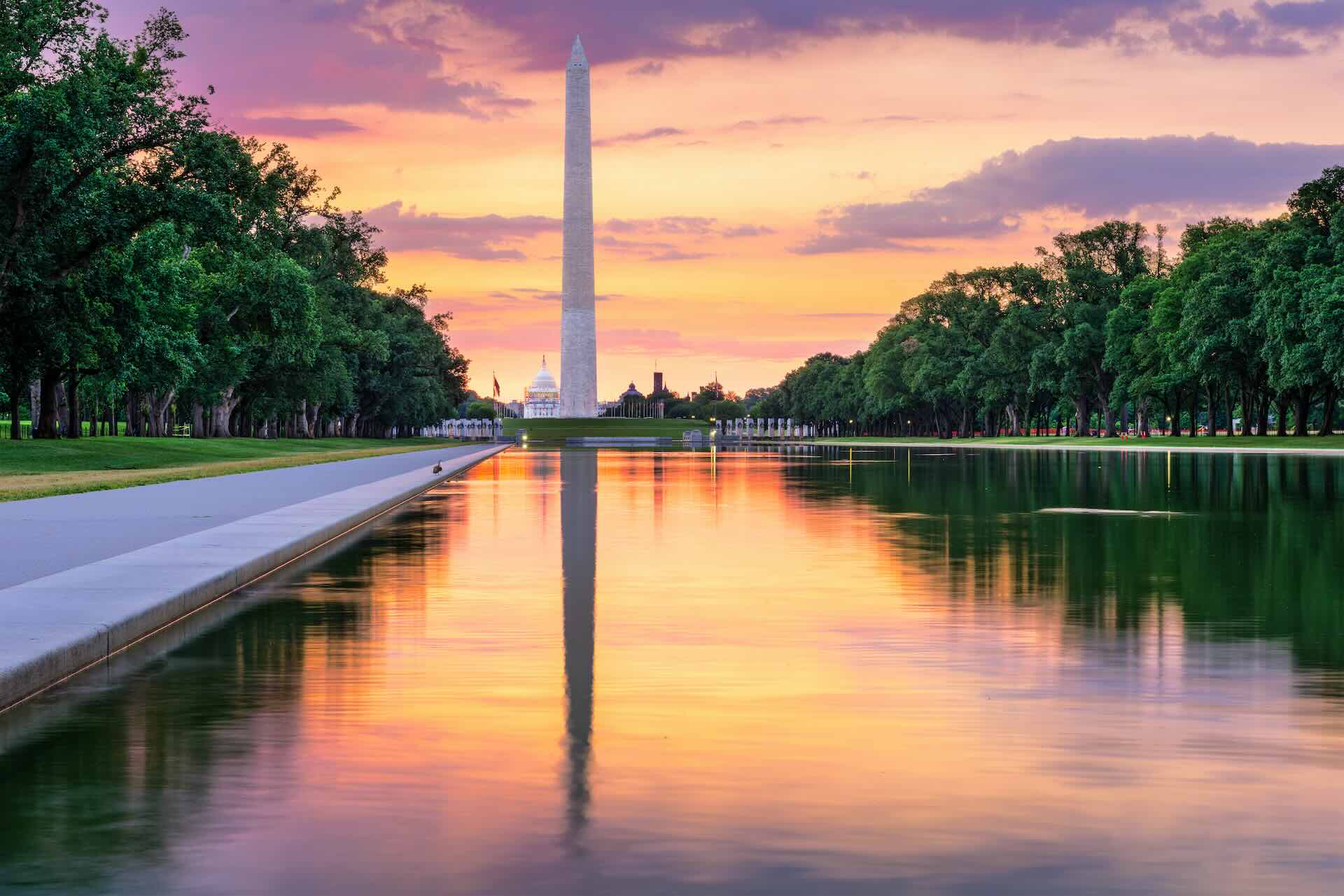 The Washington Monument reflecting on the water with a purple sky.